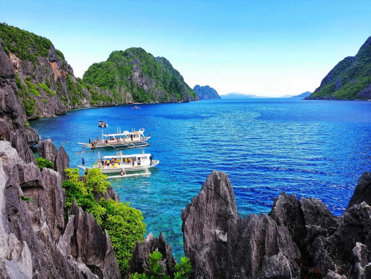 White Boats On Sea Near The Gray Rock Formation
