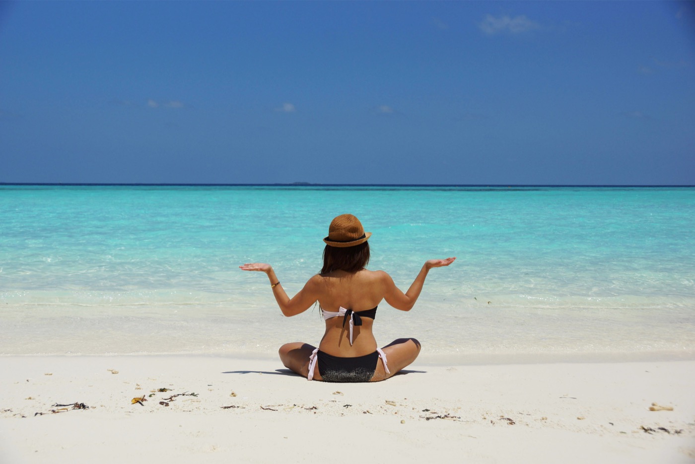 Woman In Black And White Bikini Sitting On White Stand Facing Beach During Daytime